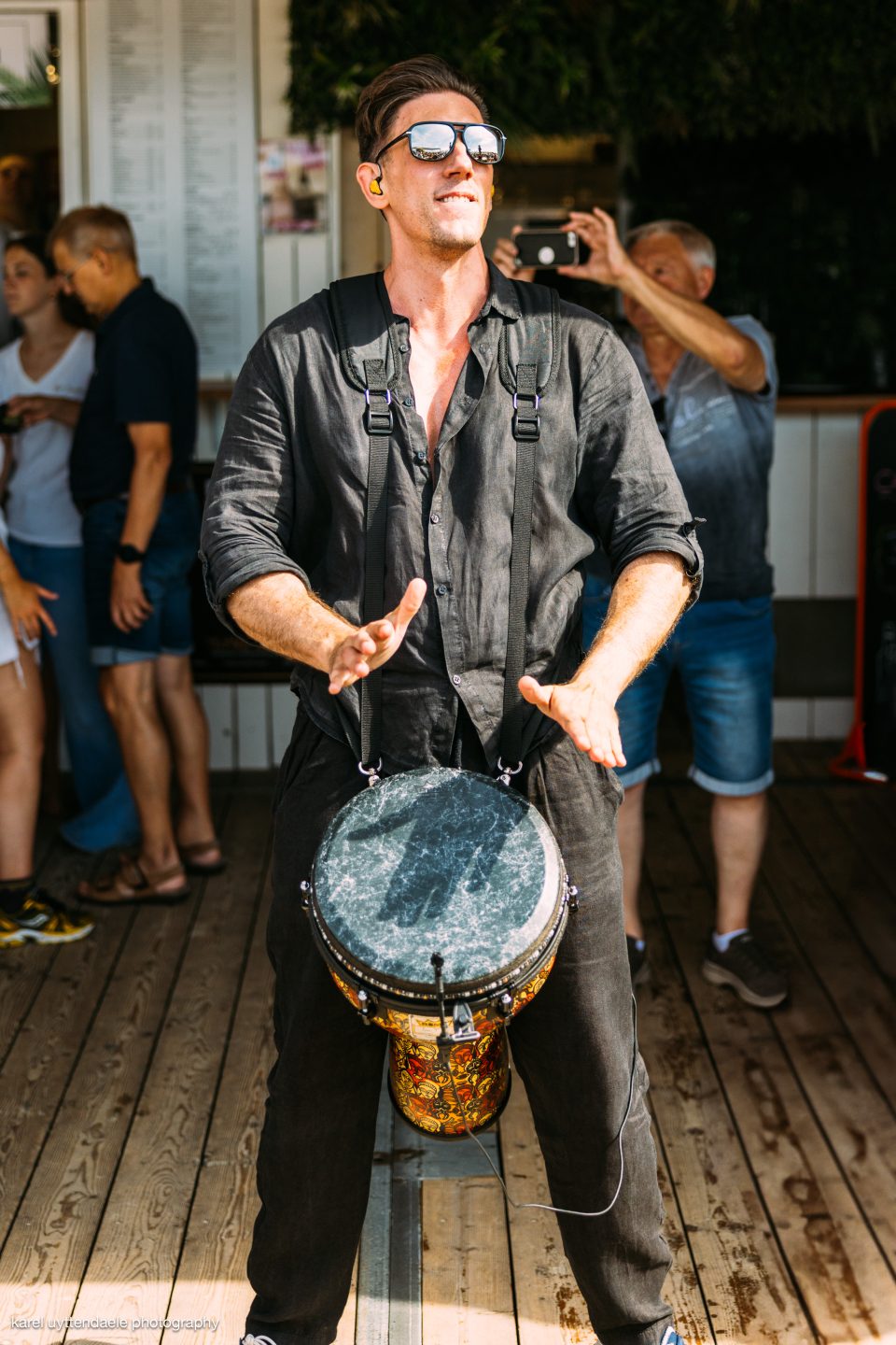 Djembe player in sunglasses performing live on a sunny terrace