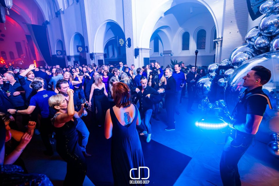 Percussionist with an LED djembe on a packed dance floor at an evening party