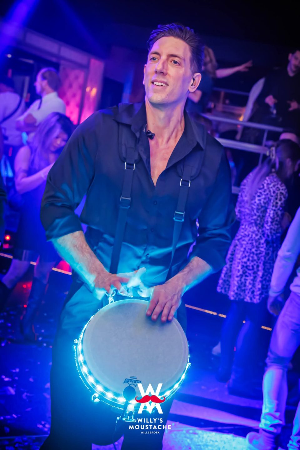 Percussionist playing live on a blue-lit LED djembe in a club