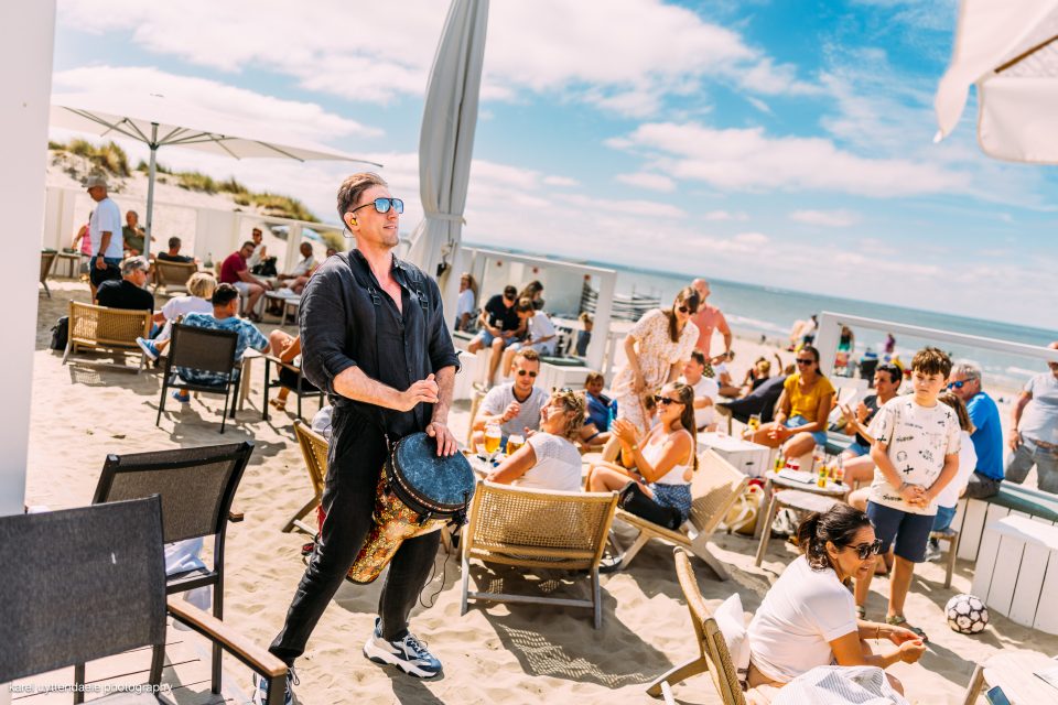 Live djembe among guests on a sunny beach terrace by the sea