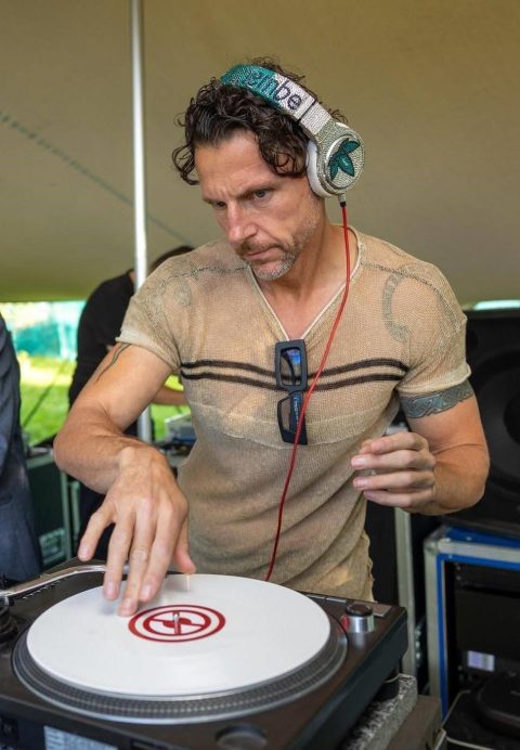 Kevin Kinembe spinning vinyl with headphones on