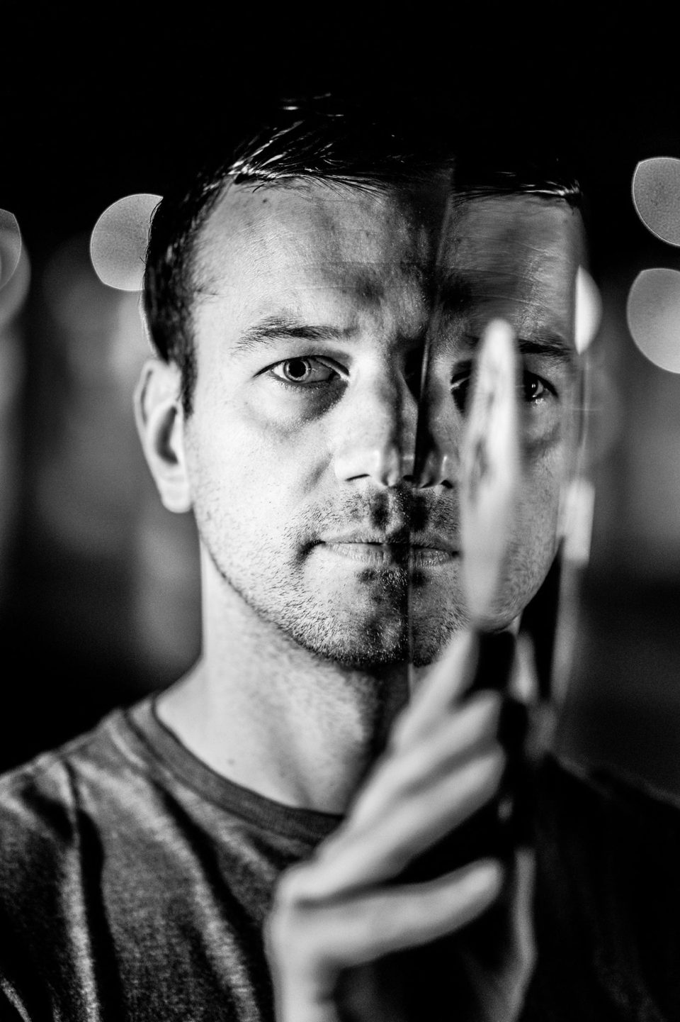 Black and white portrait of M-aximm with a hand in front of his face