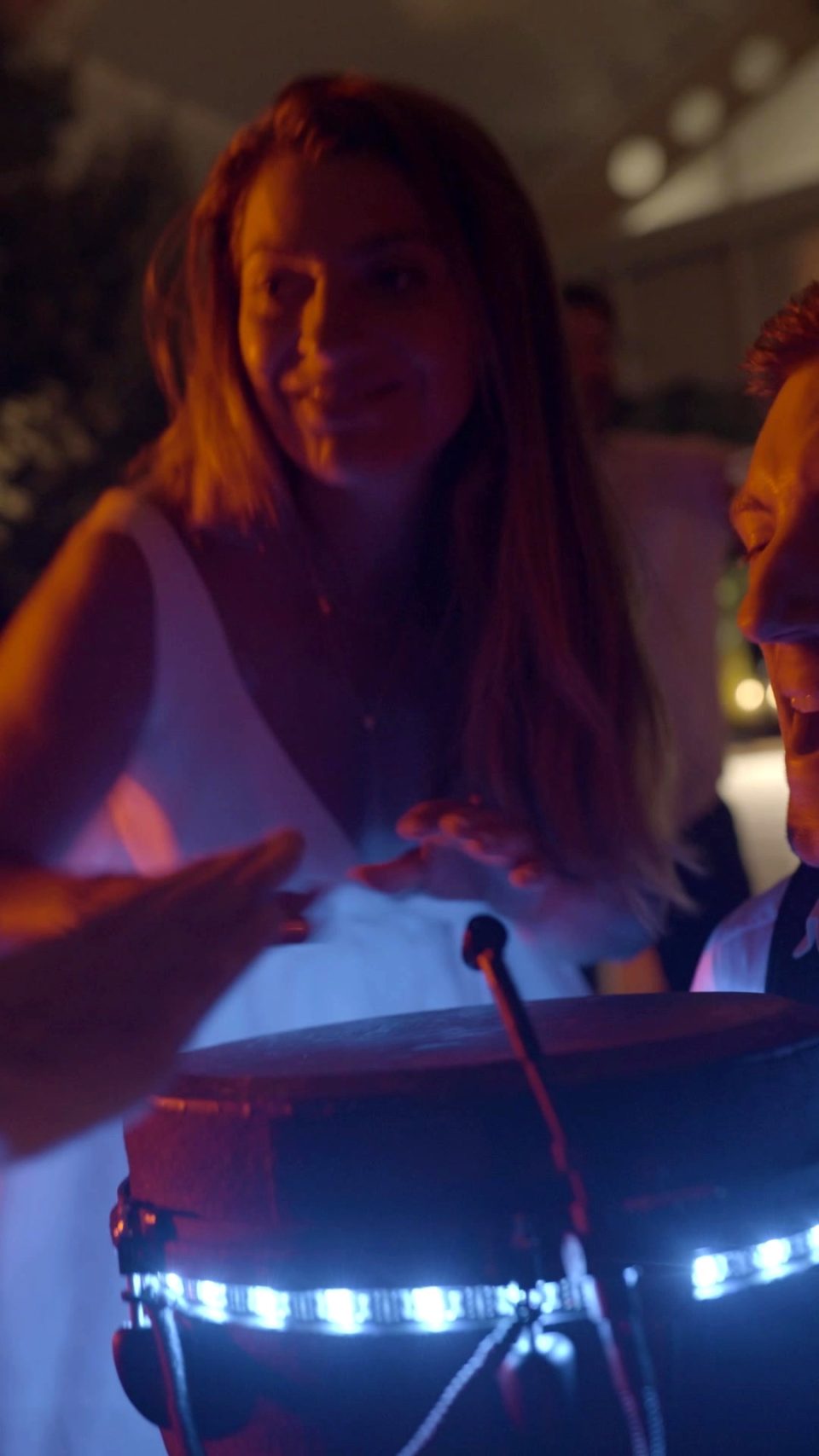 Smiling bride in a white dress playing Sam Anderson's LED djembe