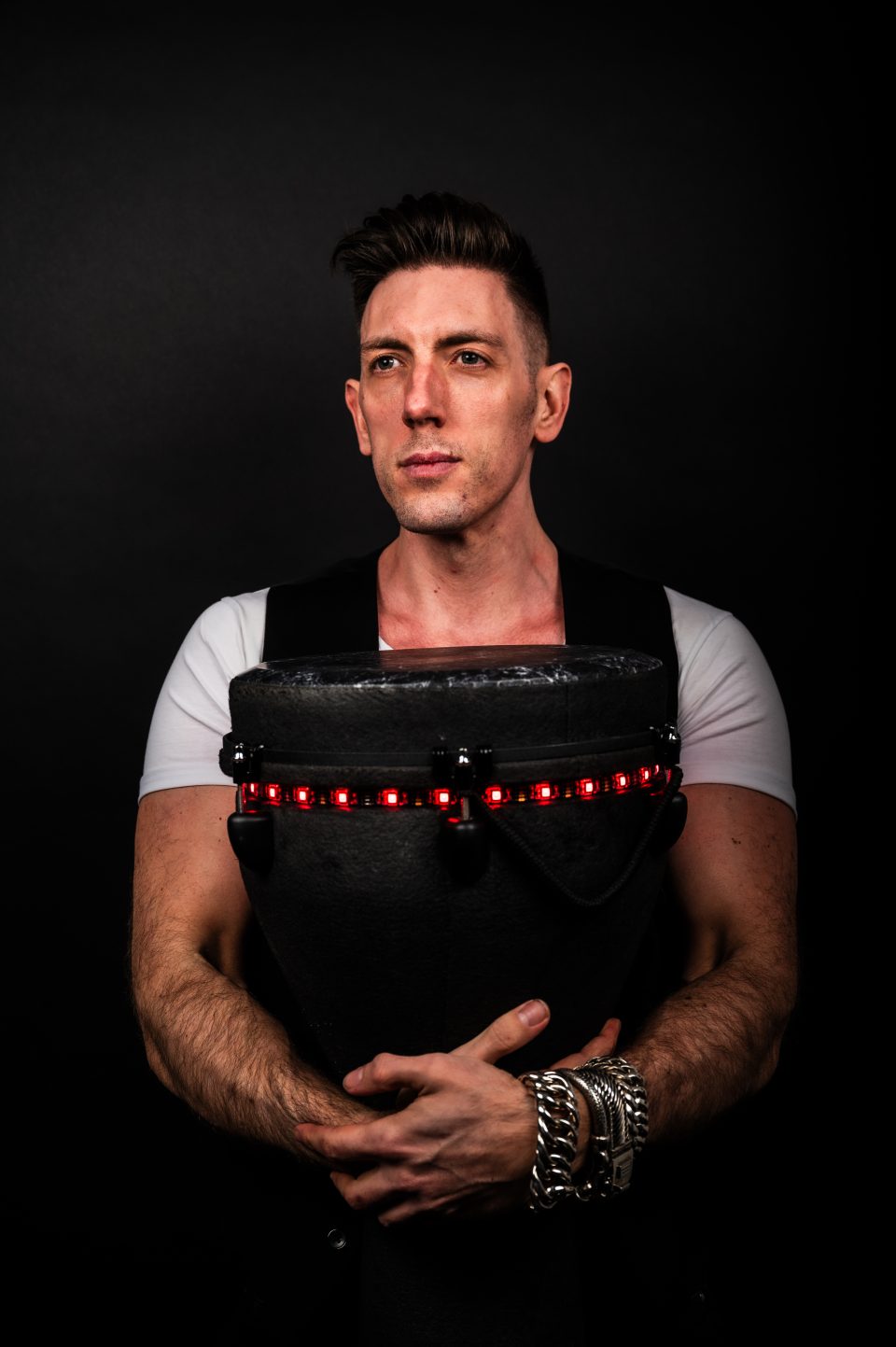 Portrait of a percussionist embracing his red-lit LED djembe