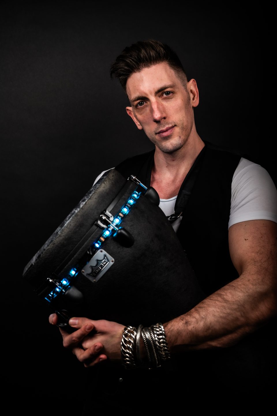 Studio portrait of a percussionist holding a blue-lit LED djembe