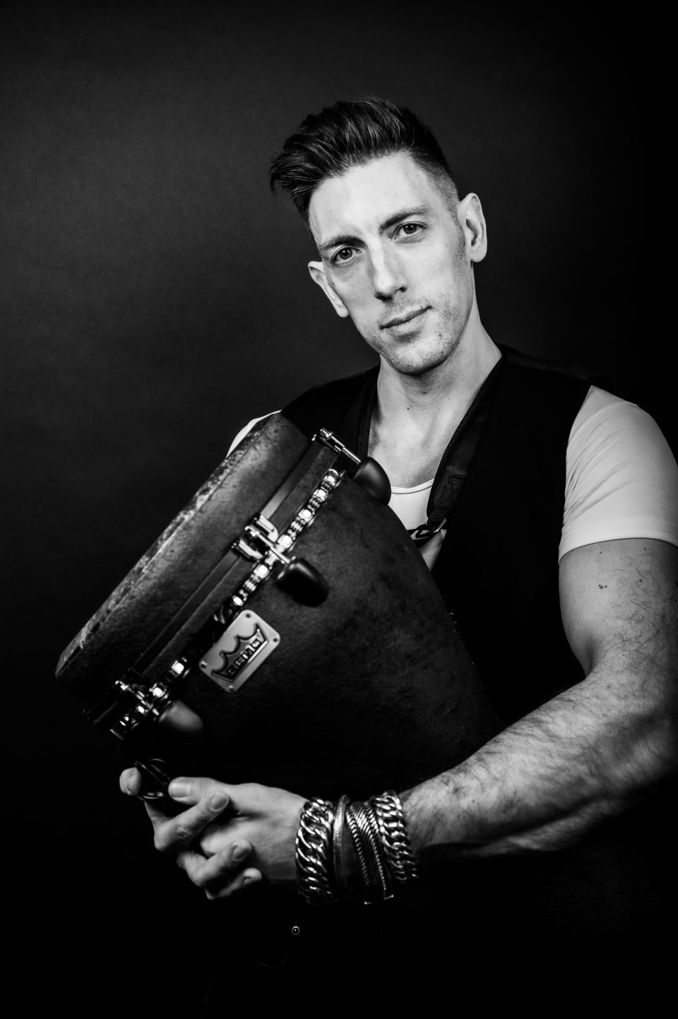 Black-and-white studio portrait of percussionist Sam Anderson with his djembe