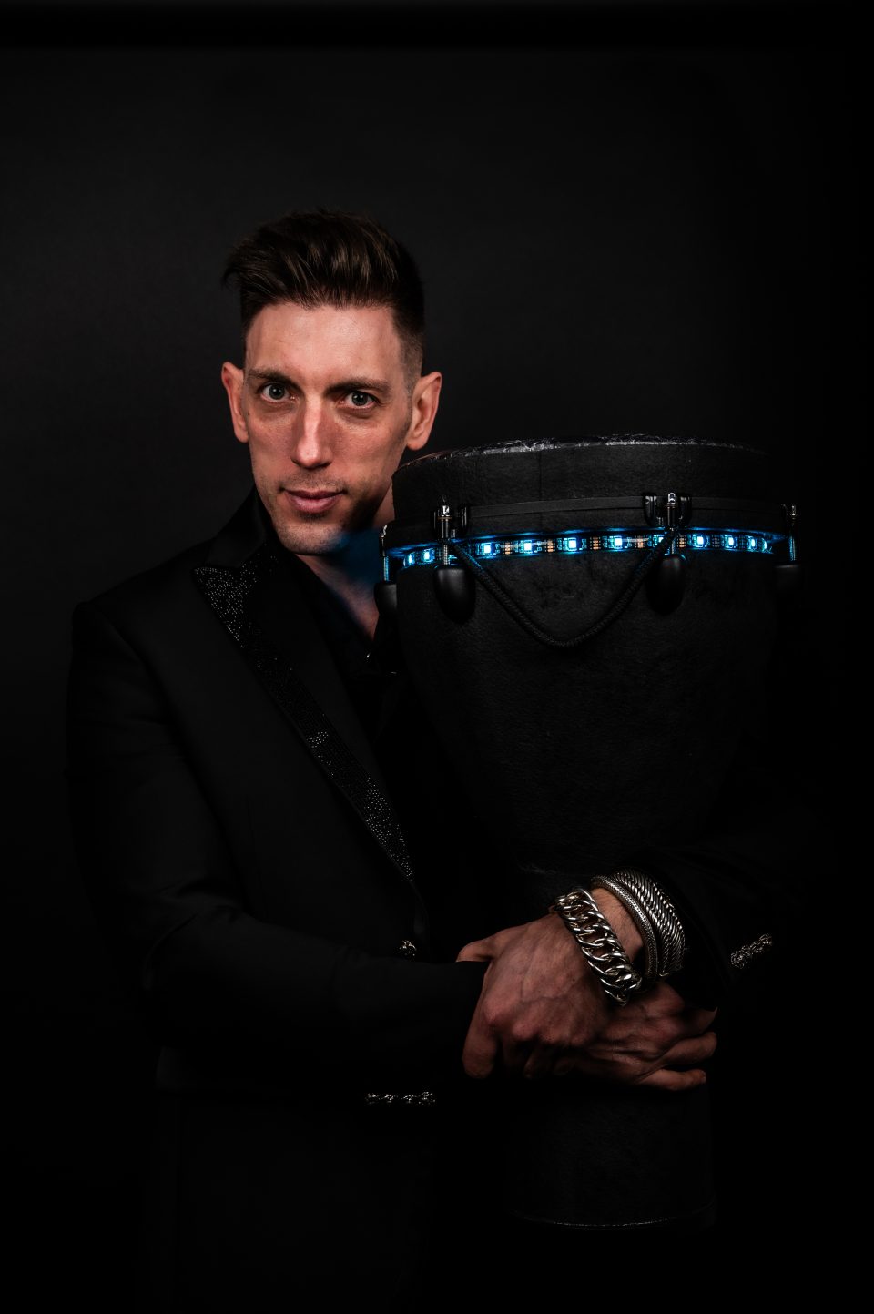 Percussionist in a suit with a blue-lit djembe, ideal for corporate events