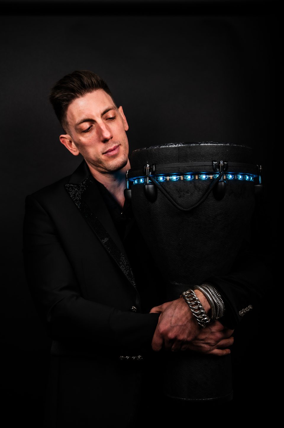 Moody portrait of percussionist Sam Anderson in a suit with an LED djembe